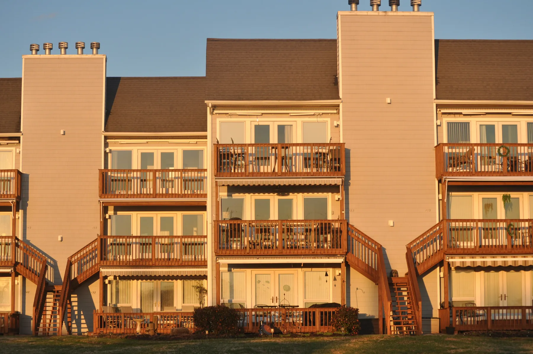 The same townhome block in wider view, two chimneys and a continuous shingle roof