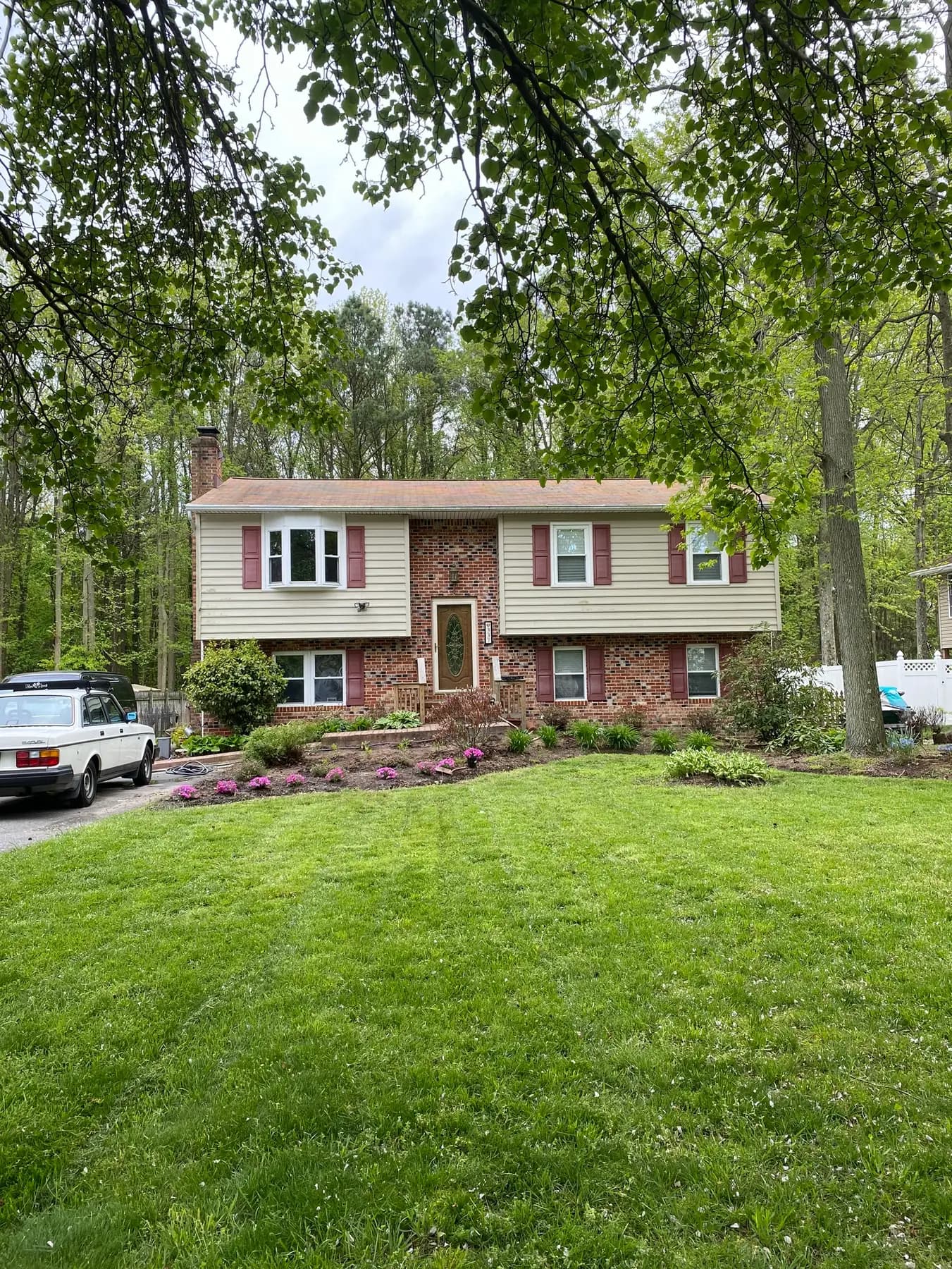 Split-level home in woodland, brick and siding front under a finished roof